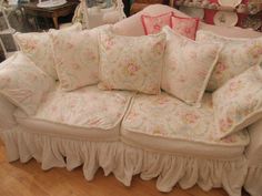 a couch with many pillows on it in a room filled with other furniture and decor