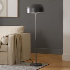 a living room scene with focus on the floor lamp and couch in the foreground