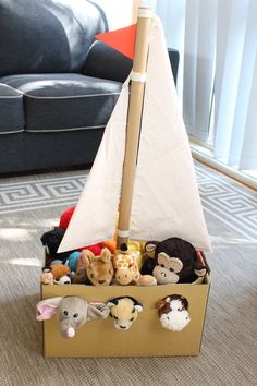 a toy boat filled with stuffed animals on top of a carpeted floor next to a couch