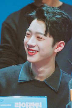 a young man smiling while sitting at a table