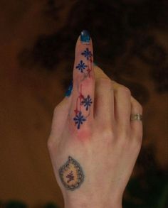 a woman's hand with blue and red designs on her nails holding up the finger