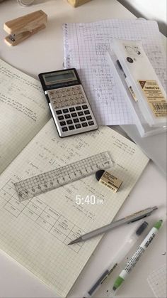 a calculator sitting on top of a notebook next to some pens and pencils