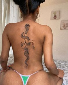 a woman sitting on top of a bed with a tattoo on her back