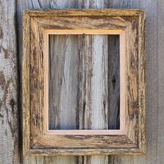 an old wooden frame hanging on the side of a building with weathered paint and wood planks