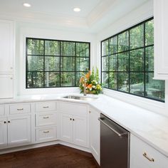 a kitchen with white cabinets and black windows