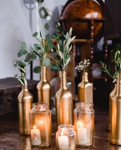 candles and vases with greenery in them on a table