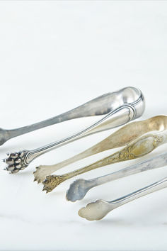 five silver spoons are lined up on a white surface