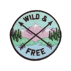 a patch that says wild and free with arrows in front of trees on the mountain