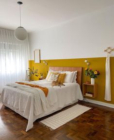 a bedroom with yellow and white walls, hardwood flooring and a bed in the corner