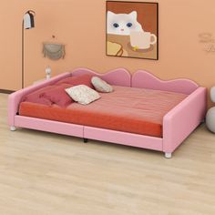 a pink bed sitting on top of a hard wood floor next to a white vase