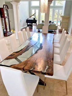 a dining room table with white chairs and a large wooden slab on the center piece