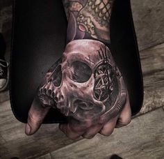 a person with a tattoo on their hand holding a clock and skull in the middle