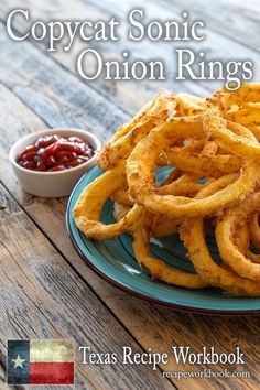 a plate with onion rings on it next to a bowl of ketchup