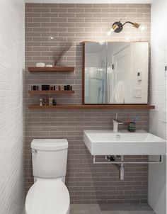 a white toilet sitting next to a sink in a bathroom under a mirror and lights