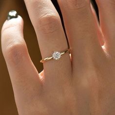 a woman's hand with a diamond ring on top of her finger and the other hand holding an engagement ring