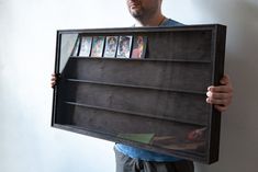 a man holding up a book shelf with pictures on it