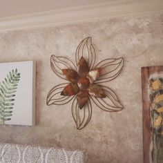 there is a metal flower on the wall next to two pictures and a fern leaf