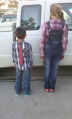 two young children standing in front of a white truck with their hands on the door