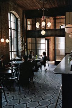 people sitting at tables in a restaurant with lots of windows on the walls and floor