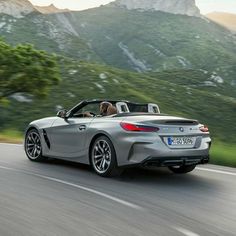 a silver convertible car driving down the road