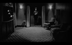 a man standing in the doorway of a dark room