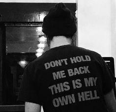 black and white photograph of man wearing t - shirt that says don't hold me back this is my own hell