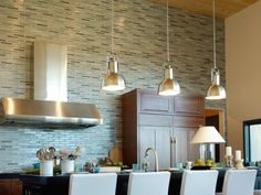 a kitchen with several lights hanging from the ceiling and white chairs in front of it