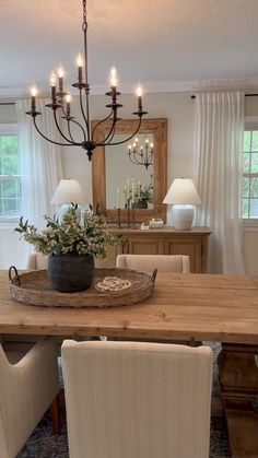 a dining room table with chairs and a tray on it's centerpiece in front of a mirror