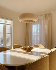 a dining room table with chairs and a bowl of fruit on top of the table