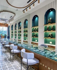 there are many chairs in the room with glass shelves full of jewelry and watches on display