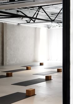 an empty room with yoga mats on the floor in front of a large white wall