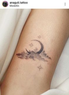 a tattoo on the leg of a woman with a crescent moon and stars above it