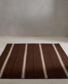 a brown and white striped rug sitting on top of a floor next to a wall