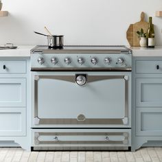 a stove top oven sitting inside of a kitchen next to blue cabinets and counter tops