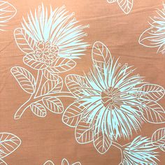 an orange and white floral print fabric with blue flowers on the top, in front of a brown background