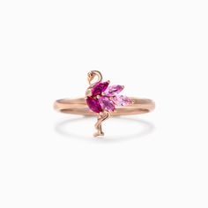 a gold ring with pink stones and a flamingo on the front, sitting on a white background