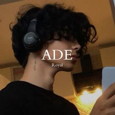 a man with headphones is looking at his cell phone and has the word ade on it