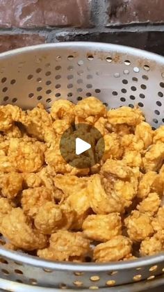 a metal basket filled with fried food next to a brick wall