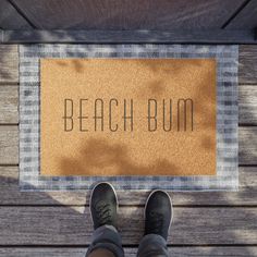 a person standing in front of a door mat that says beach bum