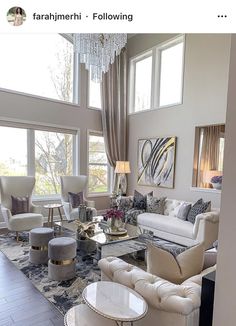 a living room filled with lots of furniture next to large window covered in curtains and chandelier