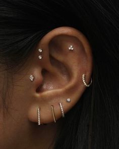 a woman with three piercings on her ear and one behind the ear is an ear cuff