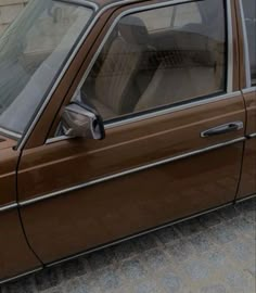 a brown car parked in front of a brick building with its door open and the driver's seat up