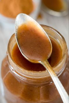 a spoon is in a jar filled with peanut butter and cinnamon sauce on a table