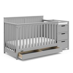 a baby crib with drawers in front of it and the bottom drawer is open