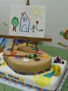 a birthday cake with an easel and paintbrush on it