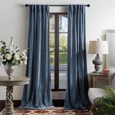 a living room filled with furniture and a large window covered in blue drapes