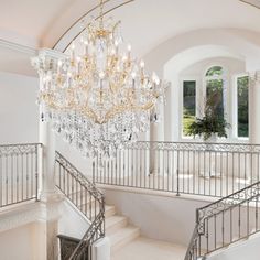 a chandelier hanging from the ceiling in a room with white walls and stairs