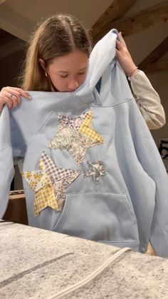 a woman holding up a blue shirt with stars on it