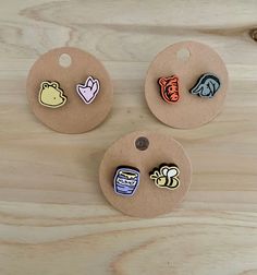 three wooden buttons with different designs on them sitting on top of a piece of wood