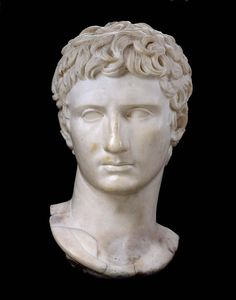 a white marble bust of a man with curly hair and eyes closed on a black background